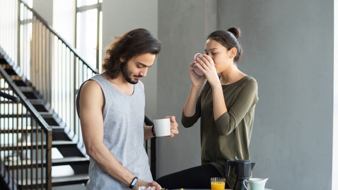 A couple enjoying a cozy breakfast with coffee and juice in their modern home kitchen.